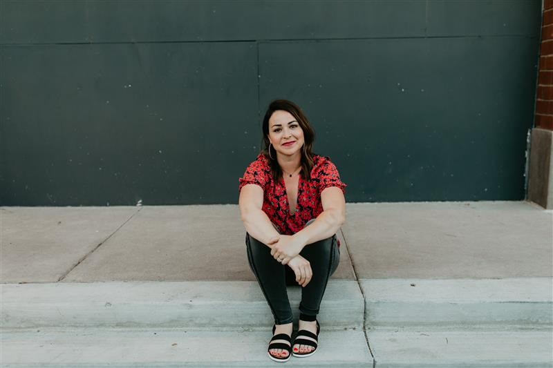 Sarah Warner seated outdoors in front of a dark green wall